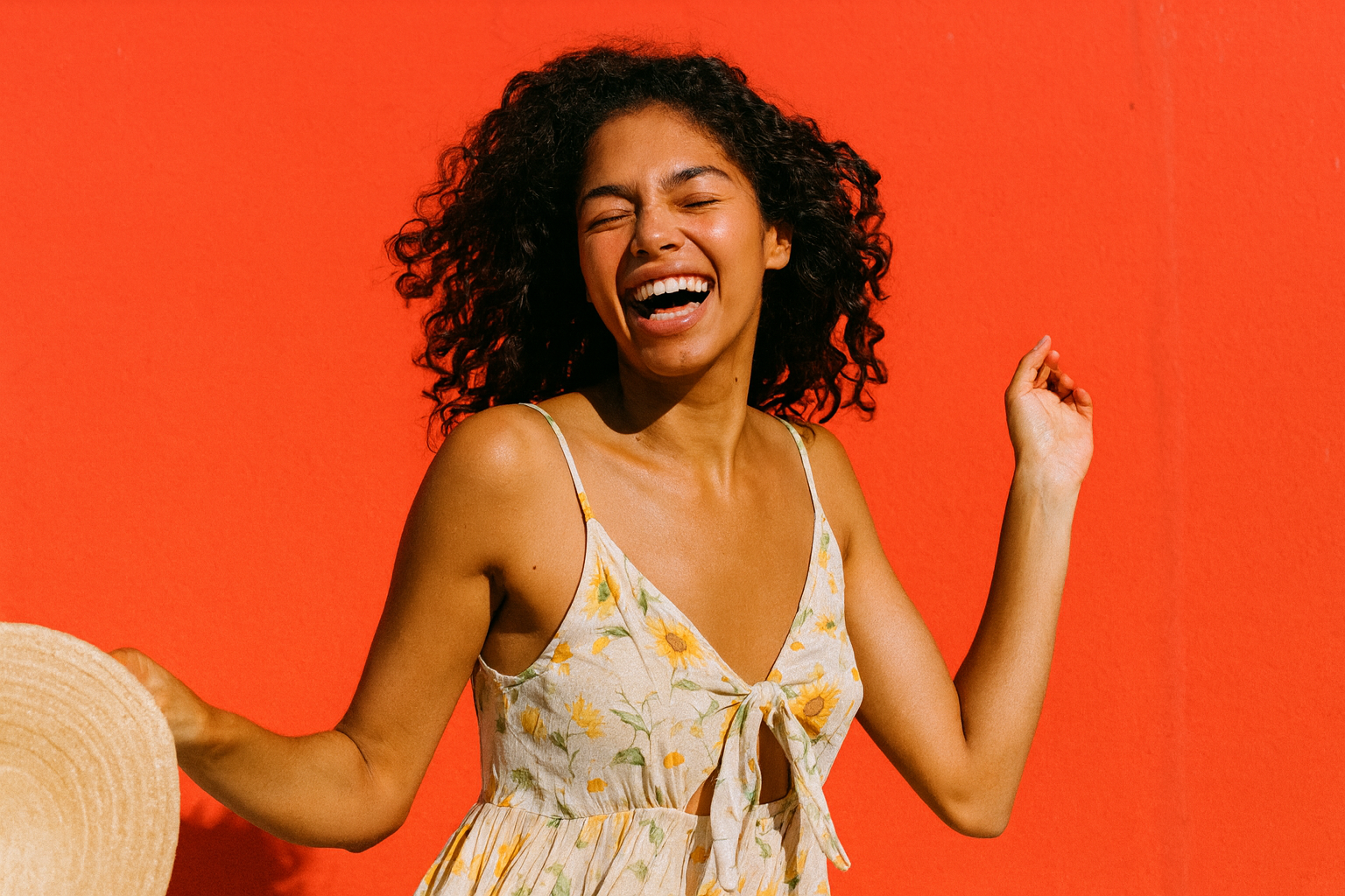 Mira dançando ao sol de vestido de verão, rindo, parede vermelha